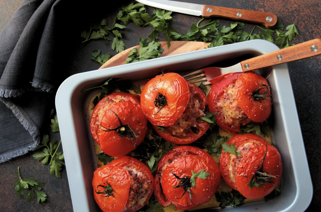 Pečen polnjen paradižnik v pekaču, zraven začimbe in nož
