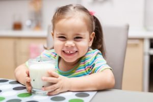 Nasmejana deklica pije mleko