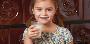 Deklica s kozarcem mleka
