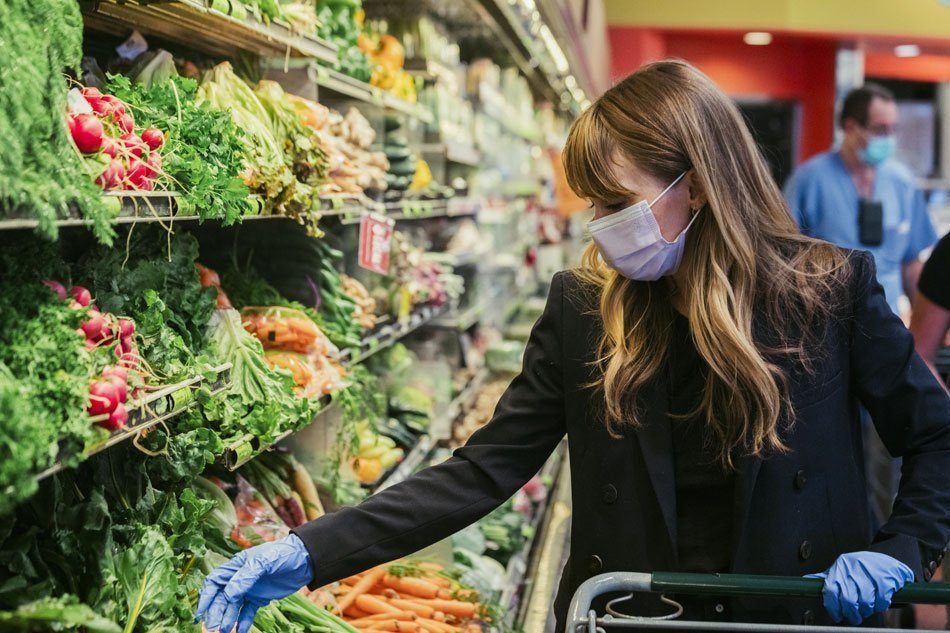 Ženska z masko, ki nosi lateks rokavice med nakupovanjem v supermarketu med karanteno koronavirusa