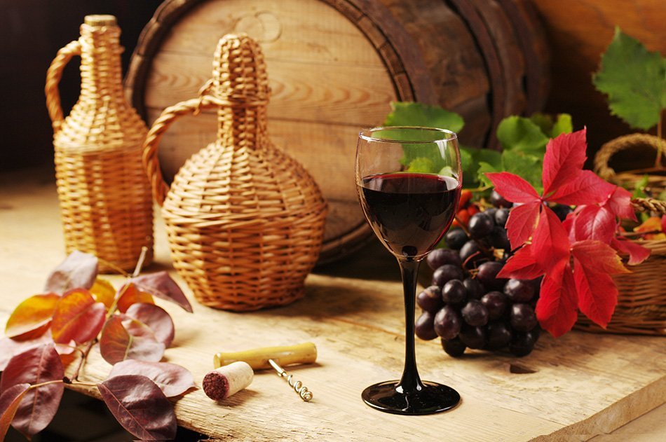 Kozarec rdečega vina, steklenica, sod vina in grozdje.